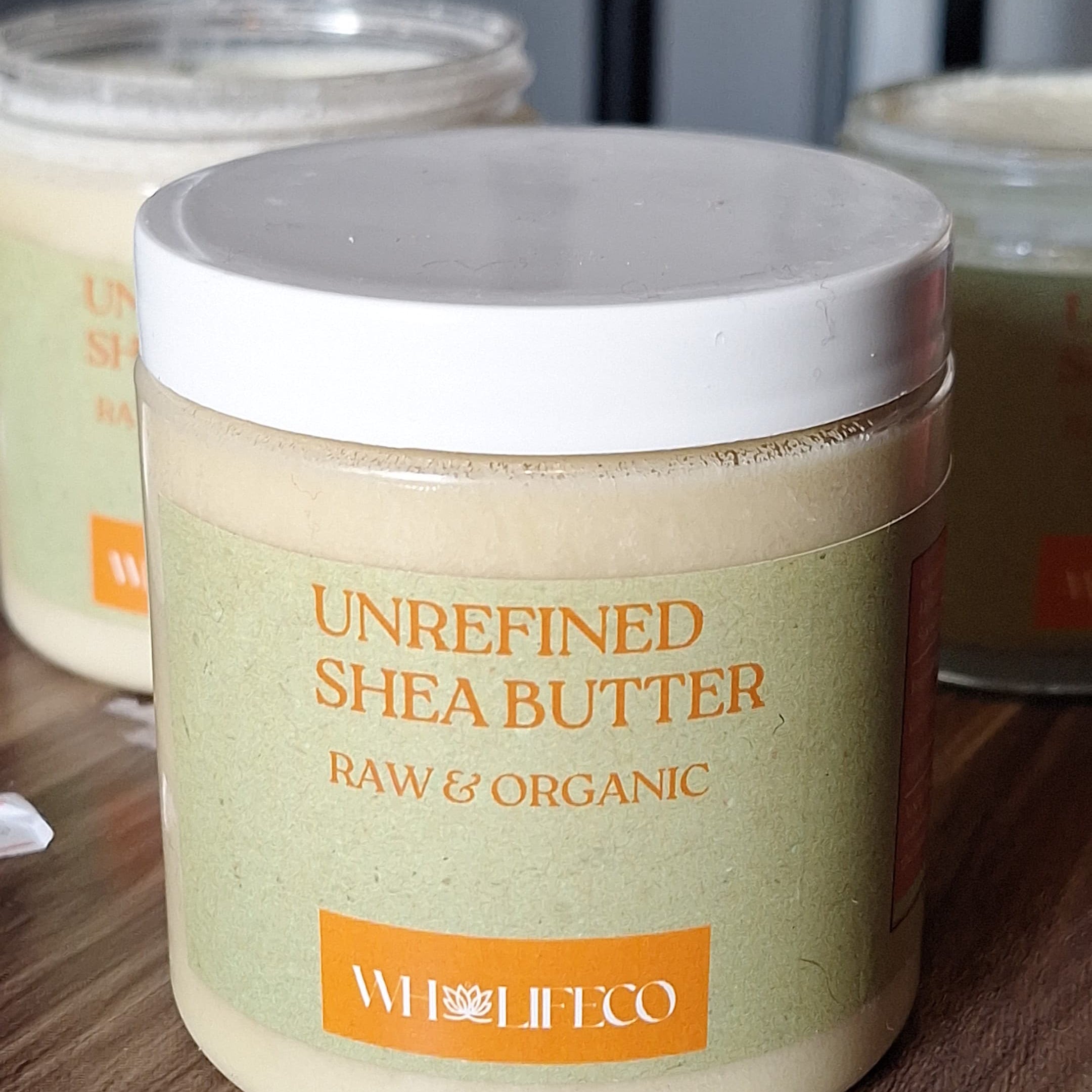 Jar of unrefined shea butter with a white lid on a wooden surface